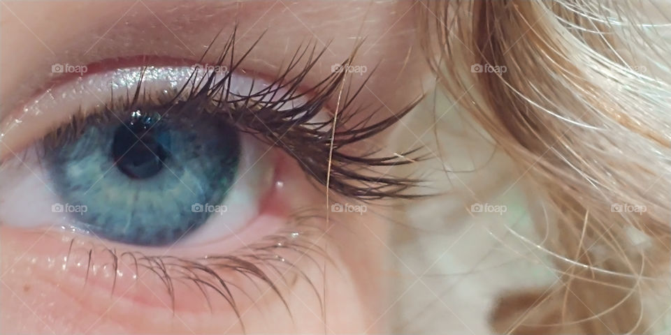 close up of a little girls crystal blue eye and long eyelashes.