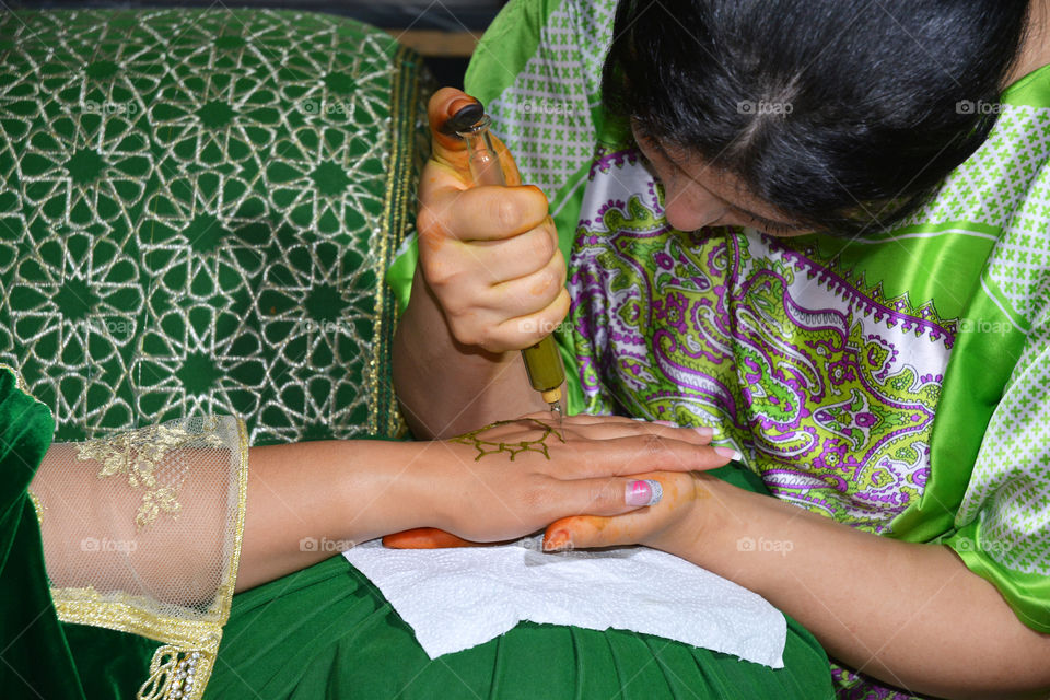 women is painting with henna on a hand before the wedding