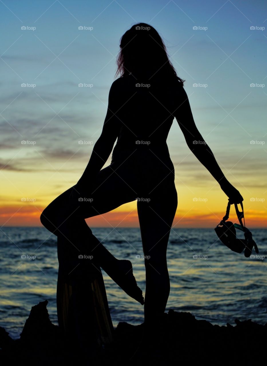 Snorkelling woman at sunset silhouette beachside
