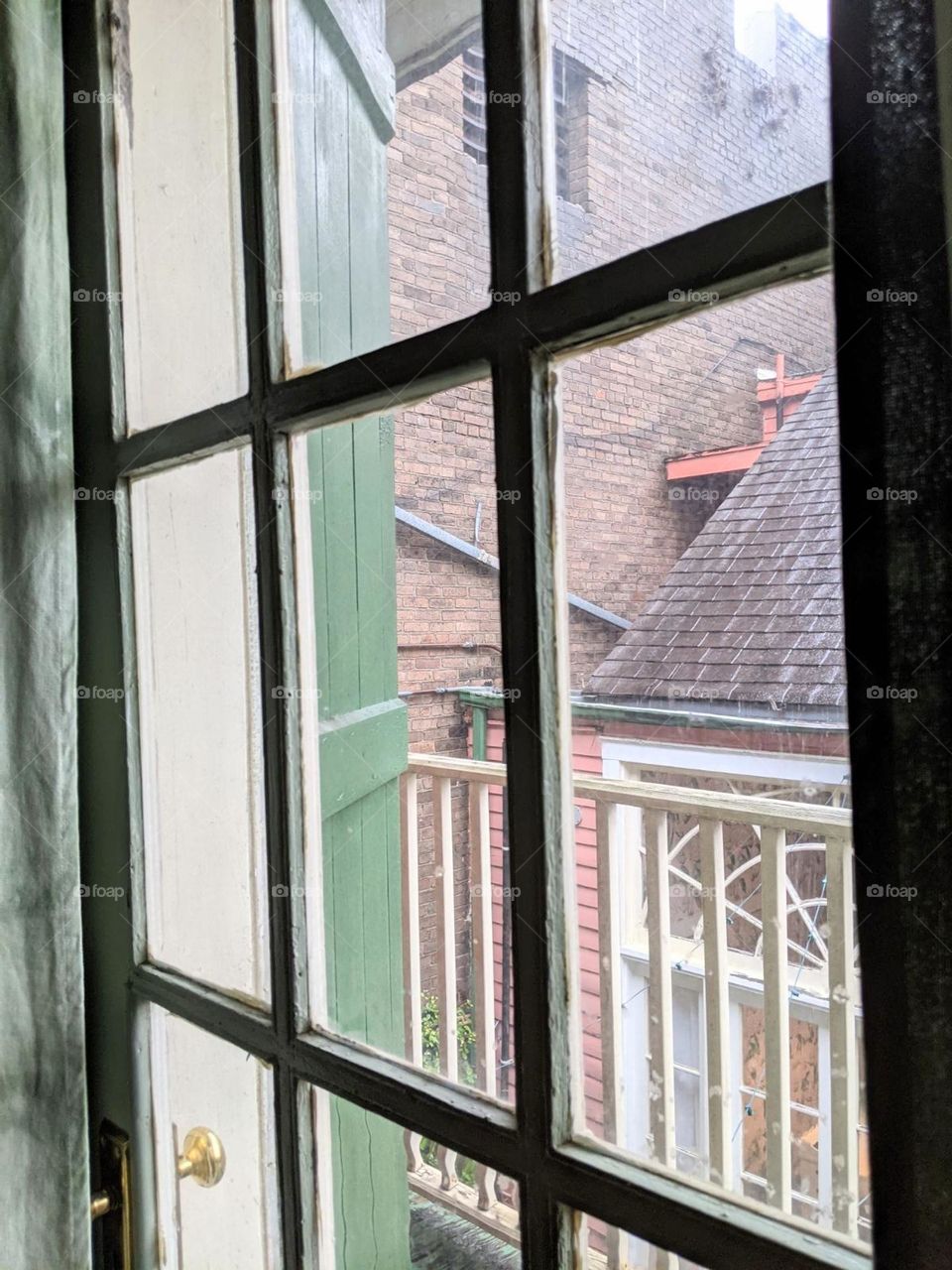 vintage house window view into courtyard Juliette balcony new Orleans rainy view window pane