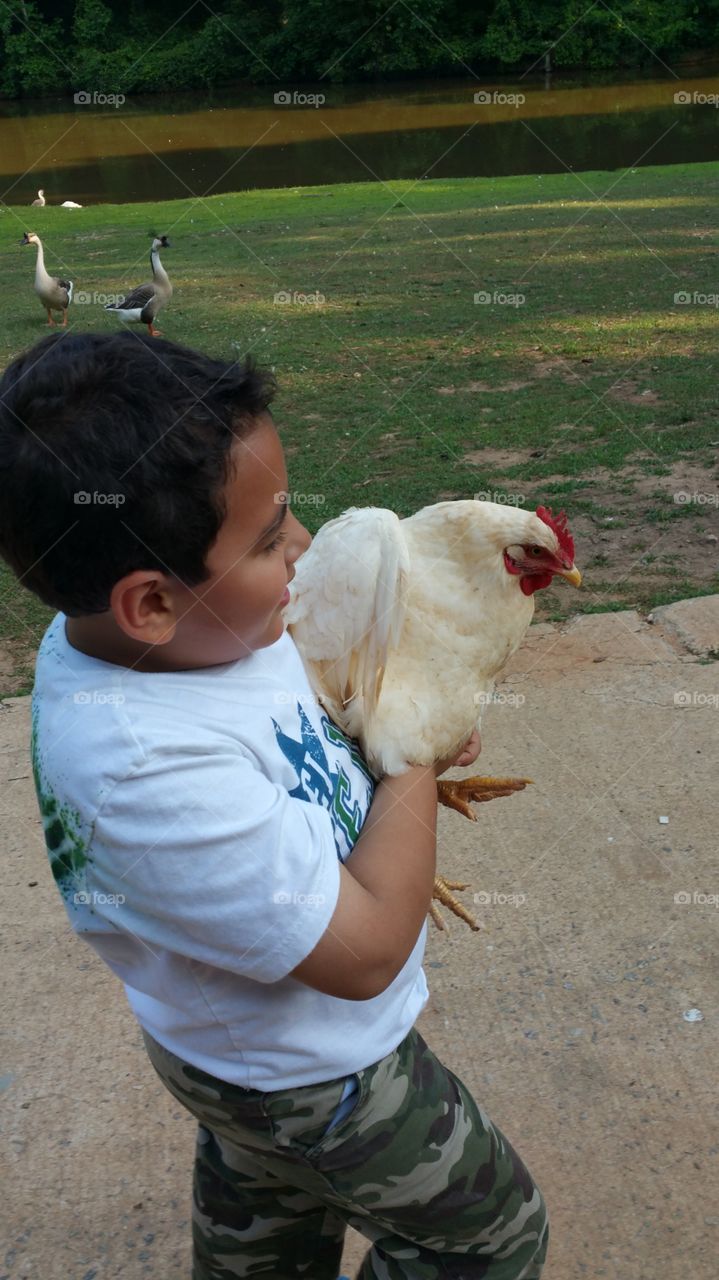 a boy caring a white chicken