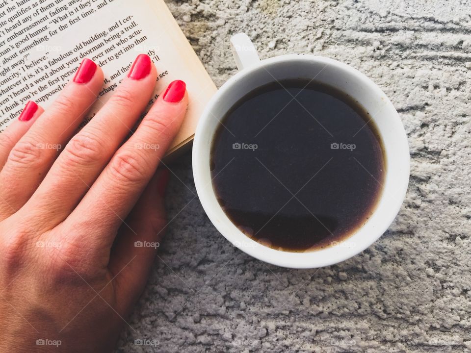 Cup of coffee with book and hand