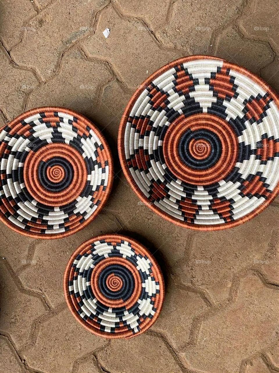 The image shows a group of hand -made dishes of wicker, decorated with colored embroideries with beautiful floral shapes, and is elegantly displayed in a warm corner that combines heritage and beauty, which gives the place an artistic spirit and attr