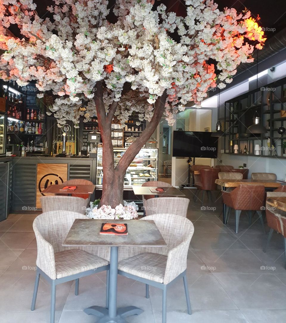 a Café with a beautiful fake tree in the middle of the room, eye- catcher