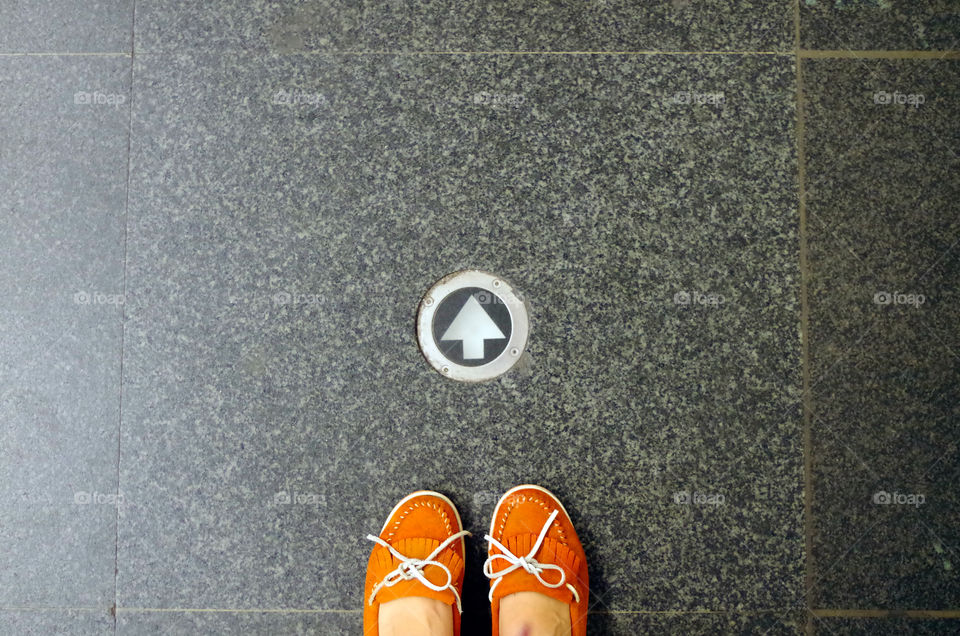 High angle view of woman wearing shoes standing by arrow sign at the metro station "Deák Ferenc tér" in Budapest, Hungary.