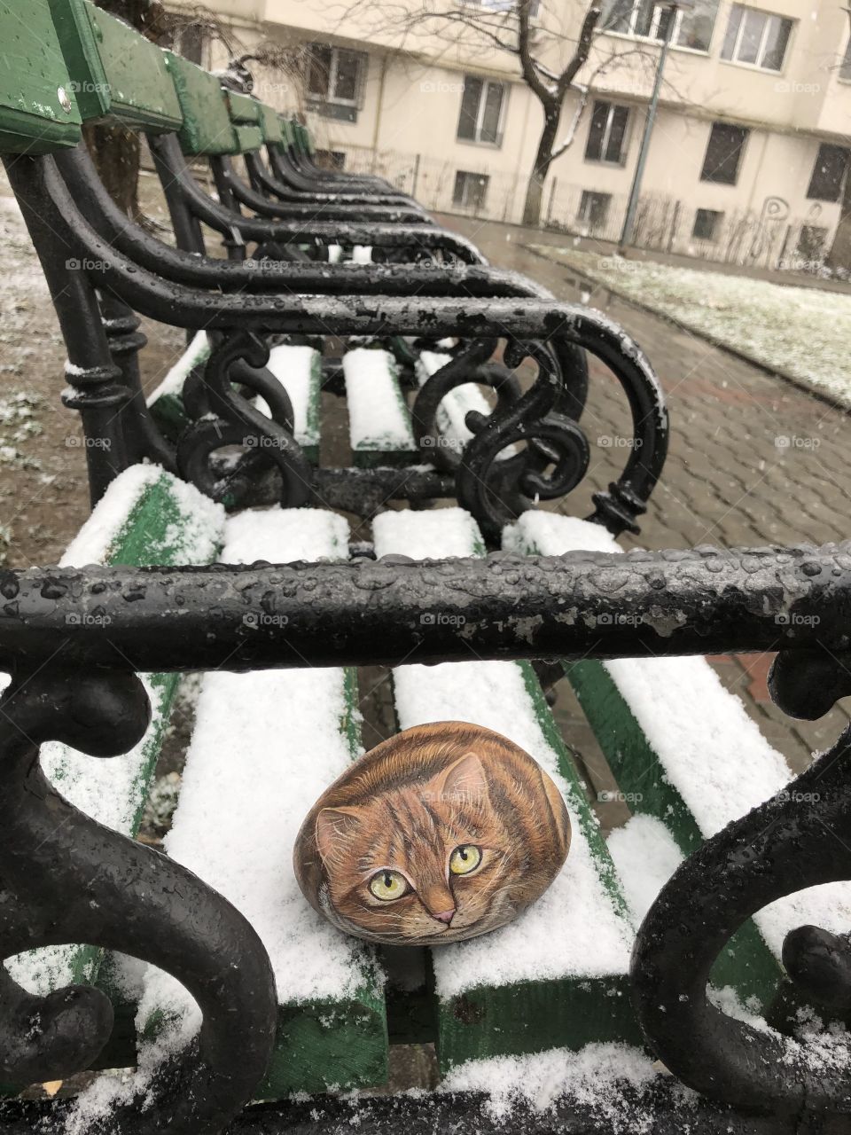 Stone cat on a snow covered public bench, Bucharest, Romania