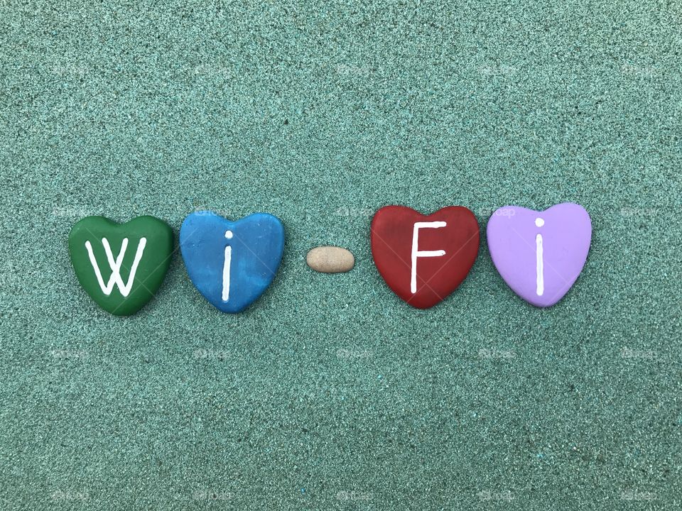 Wi-Fi with colored heart stones over green sand