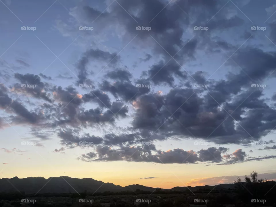A colorful sunset with clouds and mountains. 