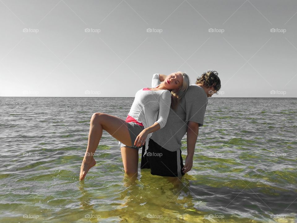 Couple back to back standing in sea