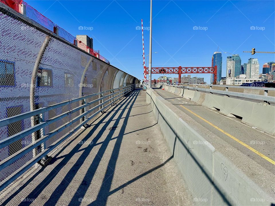 These are the pedestrian and bicycle lanes of the „Pulaski Bridge“ at „Newtown Creek“ that connects „Greenpoint“, Brooklyn and LIC, Queens. Strong shadows seamlessly merge with its structures. 2024. Hypnotic Productions