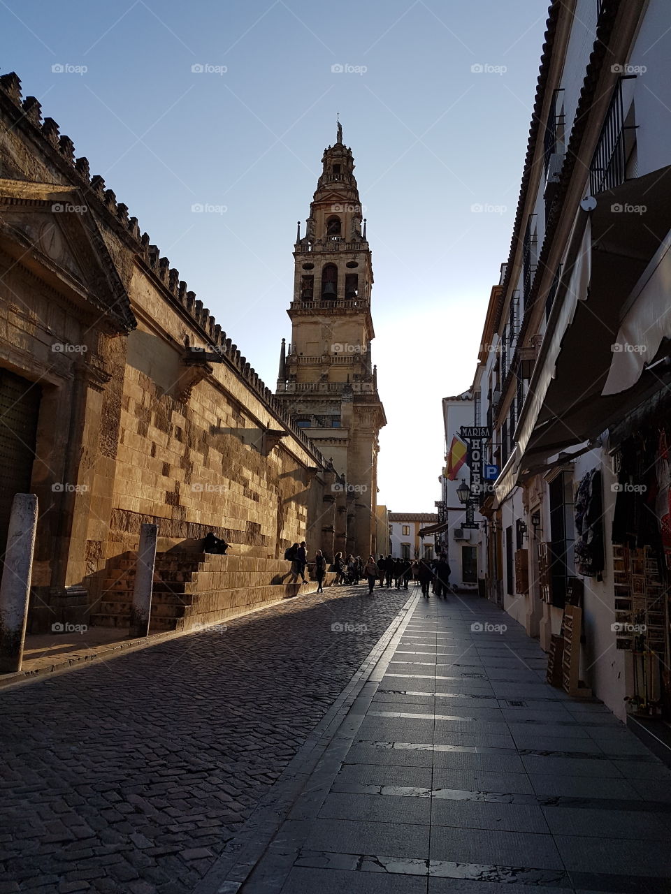 Street adjacent to the mosque-cathedral in the sunset lighting with the bell tower in background. Cordoba. Spain.