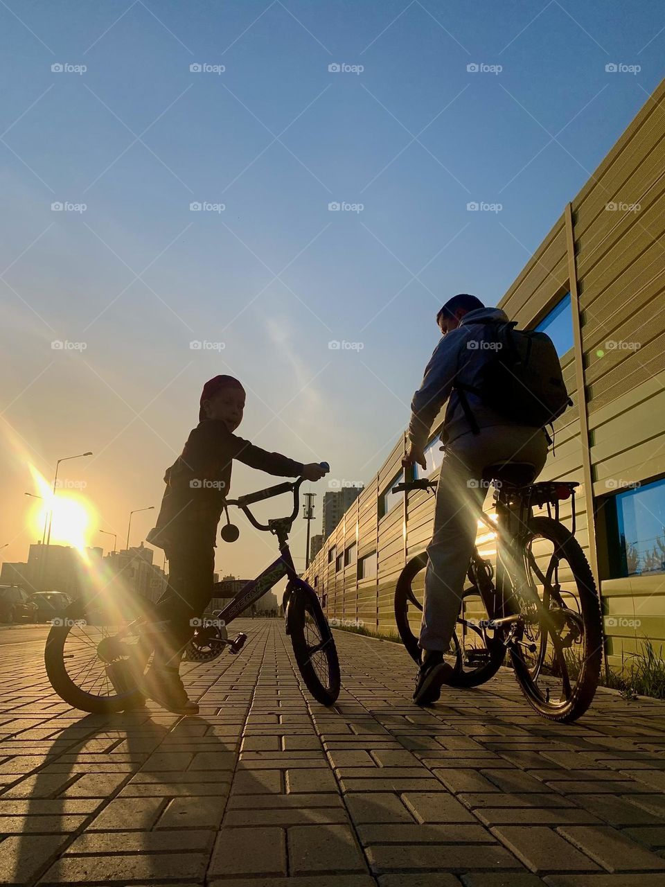 Father and son ride bicycles in the city at sunset. Summer family time and sports