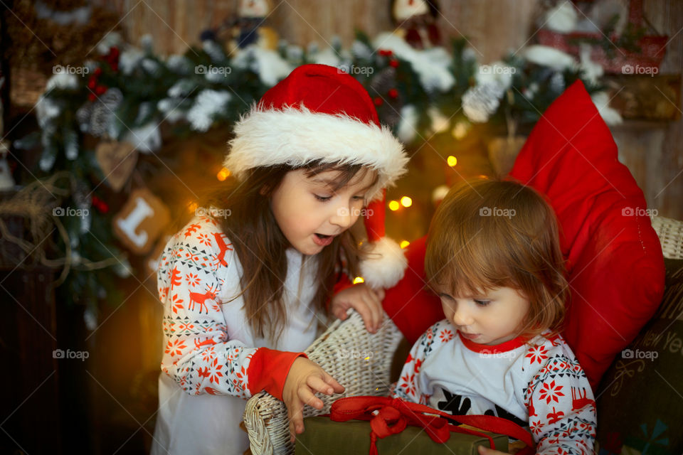 Little sisters near fireplace at Christmas Eve 