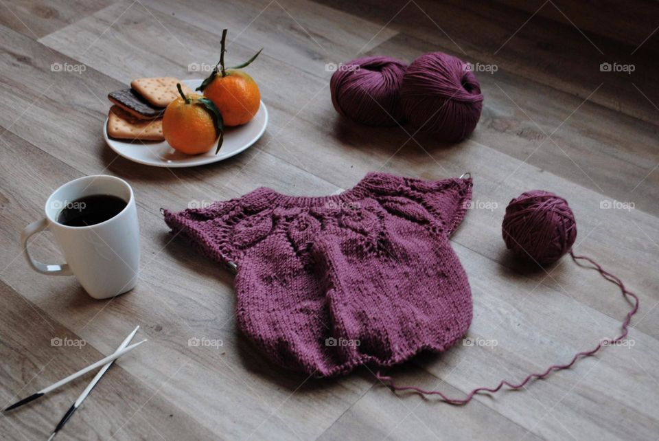 Handmade purple knitted sweater with cup of coffee and cookies and fruit 