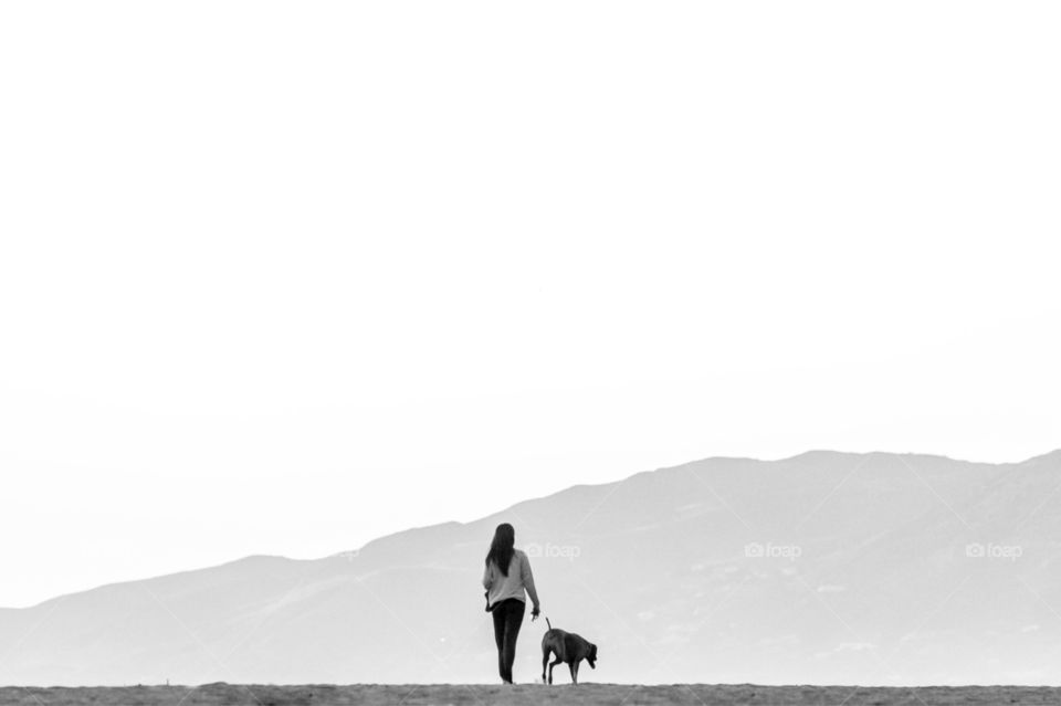 Girl walking her dog at the beach. 
