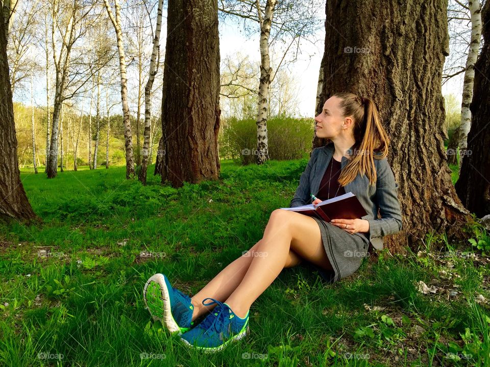 Young woman writing in her diary. Young woman writing in her diary while sitting in a parK
