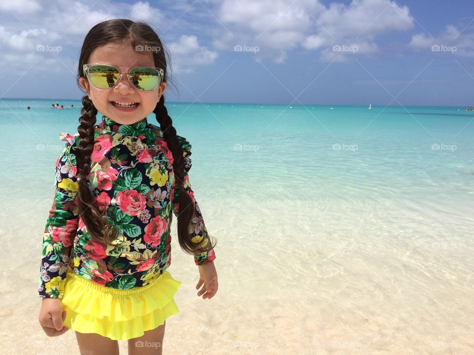 Happy girl standing in sea wearing sunglasses