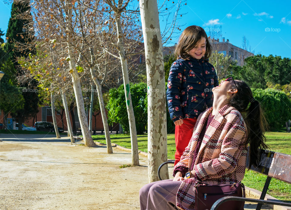 Mother and daughter laughing at a park