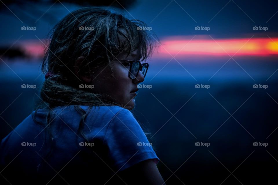 A young girl ponders as golden hour transitions to blue hour. 