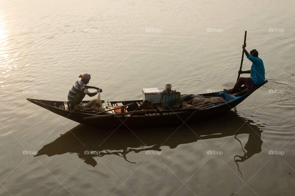 The reflection & shadows of boatman who are busy to catch fish by using cast net.