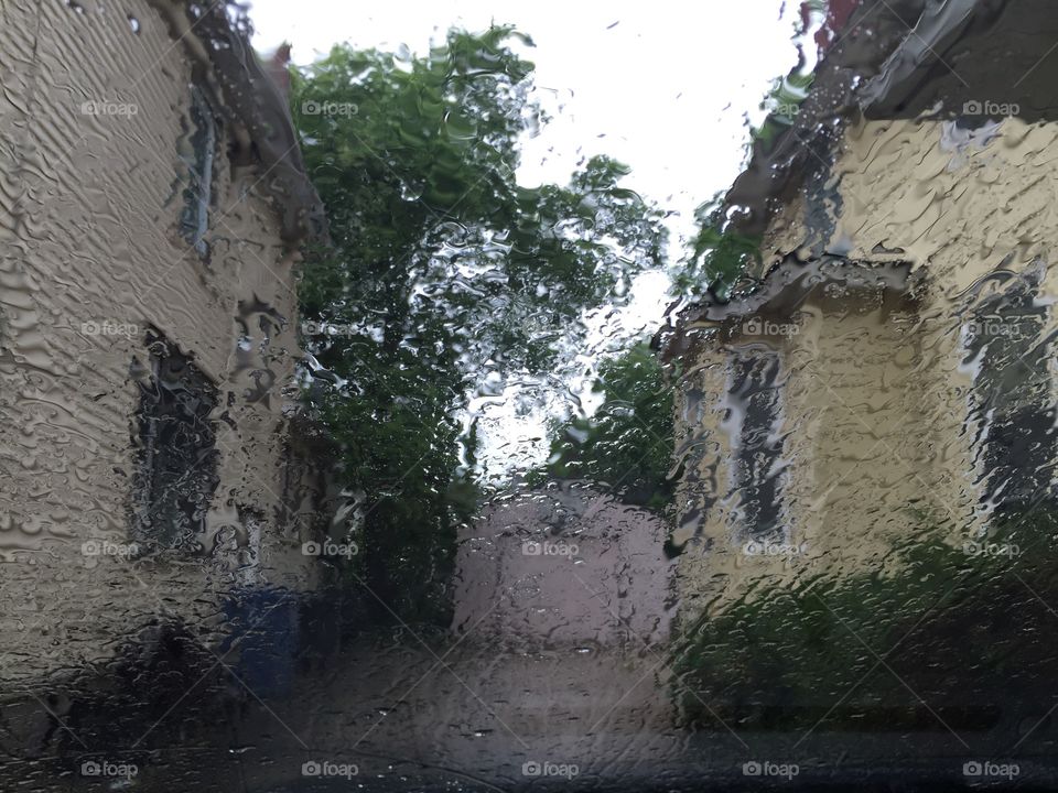 Rainy day . View of driveway through rain covered windshield