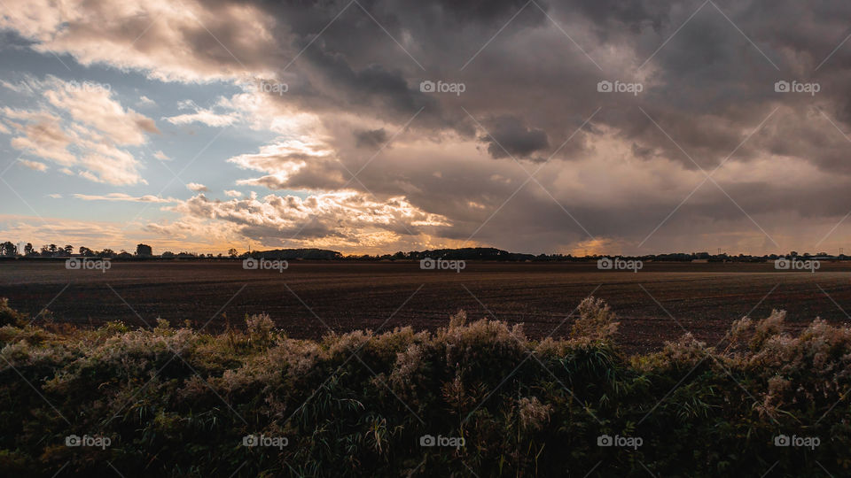 Countryside landscape with dark clouds over a farmers field 