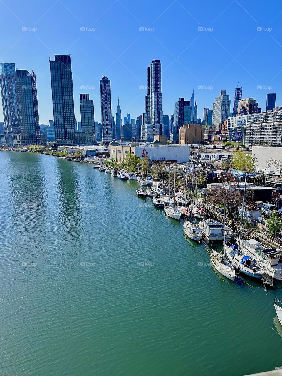 This is “Newtown Creek” seen from the “Pulaski Bridge” that connects LIC, Queens to “Greenpoint”, Brooklyn. Across the “East River” we see “Manhattan” including such landmarks as the “Empire State Building”. 2024. Hypnotic Productions