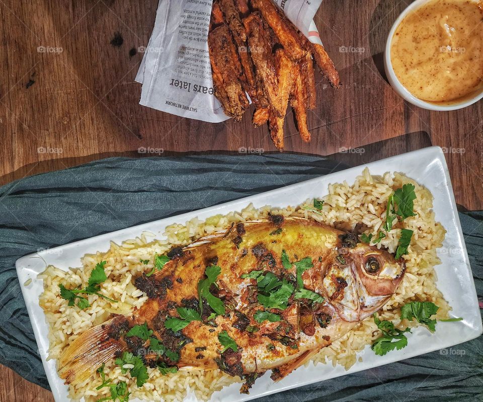 Baked whole red tilapia served on a bed of rice with carrot fries and chipotle mayo.