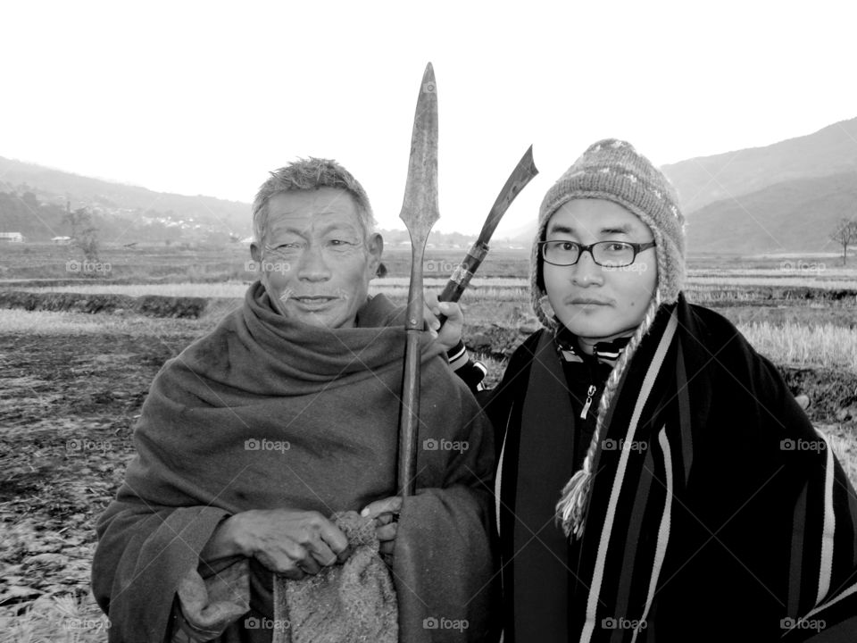 Two man standing with spear and machete weapons against mountain