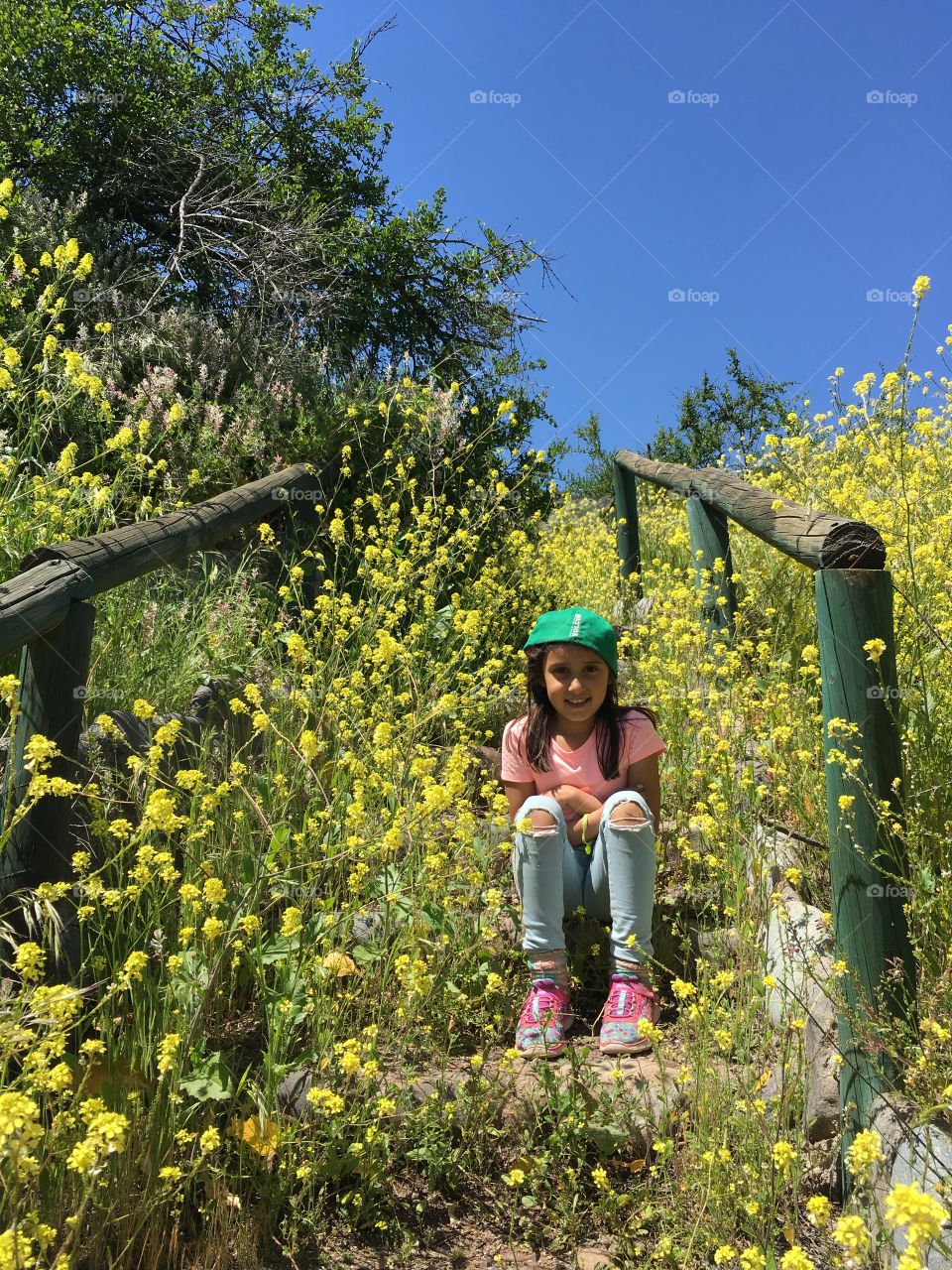 little girl sitting on ladder of yellow flowers