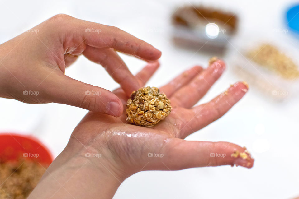 Child making raising and honey balls. Cooking in family