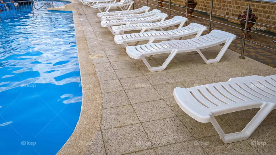 Row of free sunbeds at the swimming pool in a touristic resort.