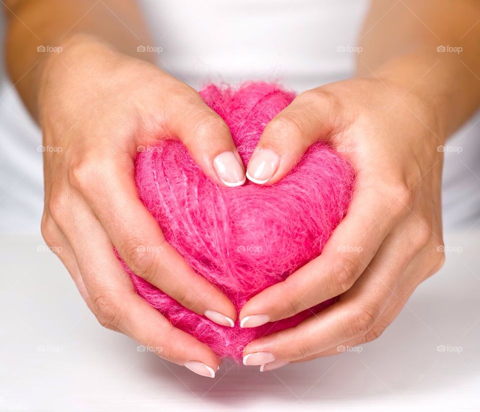 Woman holding pink heart shape ball of wool