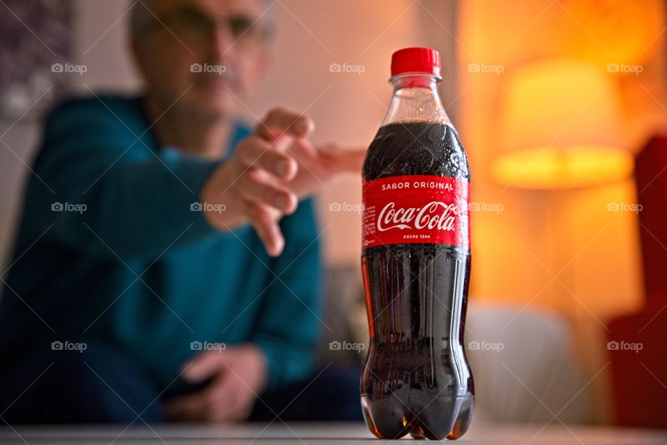 Man taking a bottle of Coca Cola in the living room