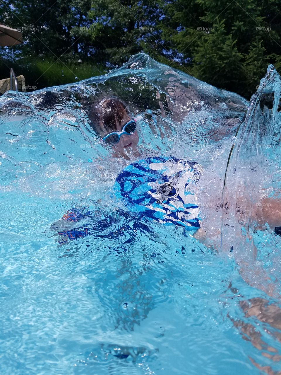 Boy with goggles having fun splashing in the pool