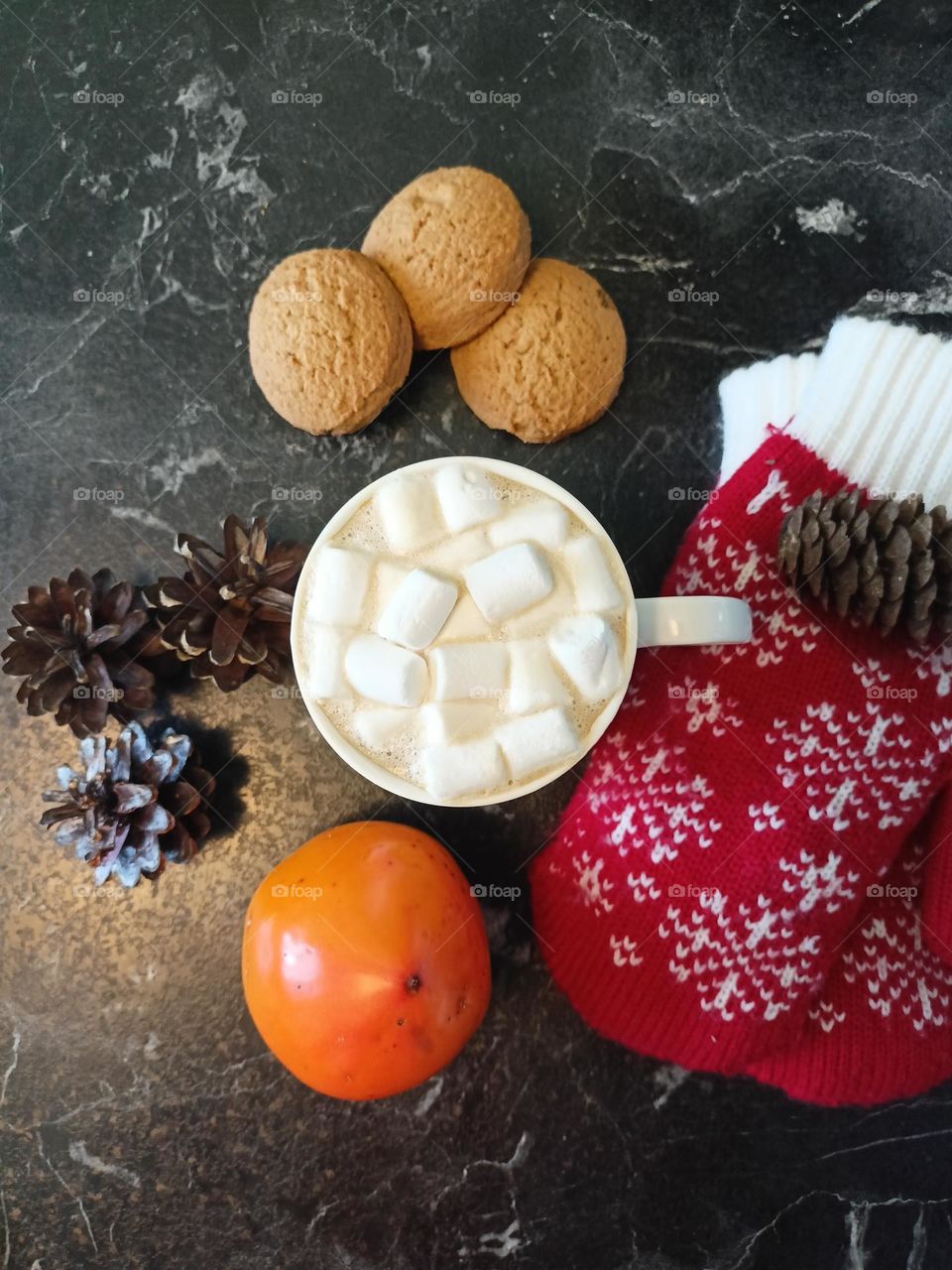 cappuccino, cones, mittens and persimmons on the table, winter mood, red bumps with white snowflakes, black background, coffee with milk, dark and cozy, coffee mug.