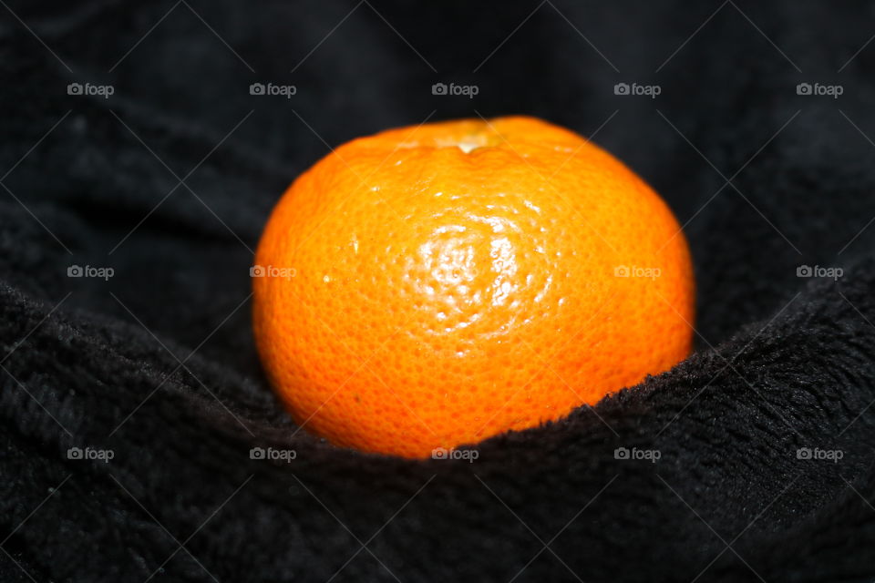 A mandarin on a soft, black blanket