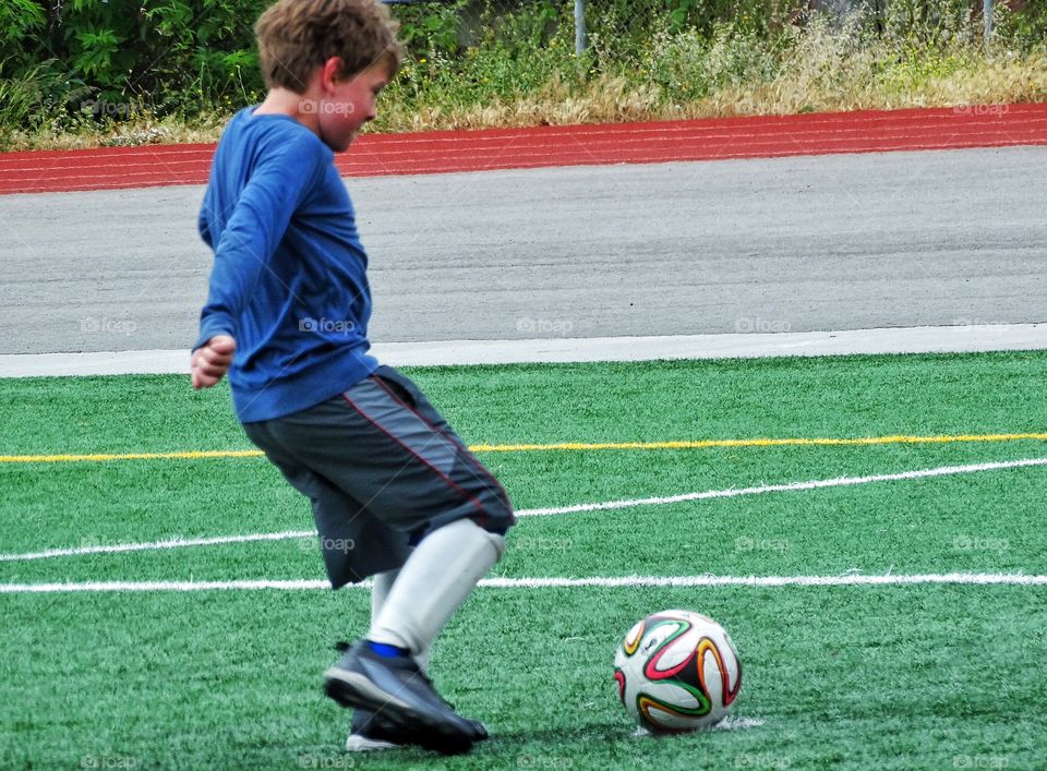 Boy Playing Soccer. Young Boy Kicking A Soccer Ball
