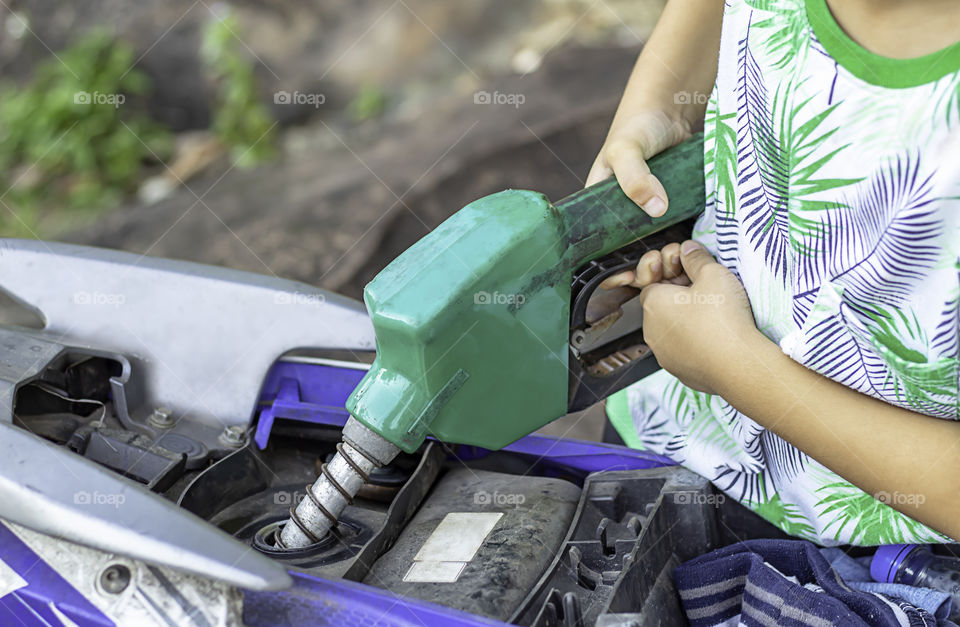 Han boy  filling up fuel into the motorbike