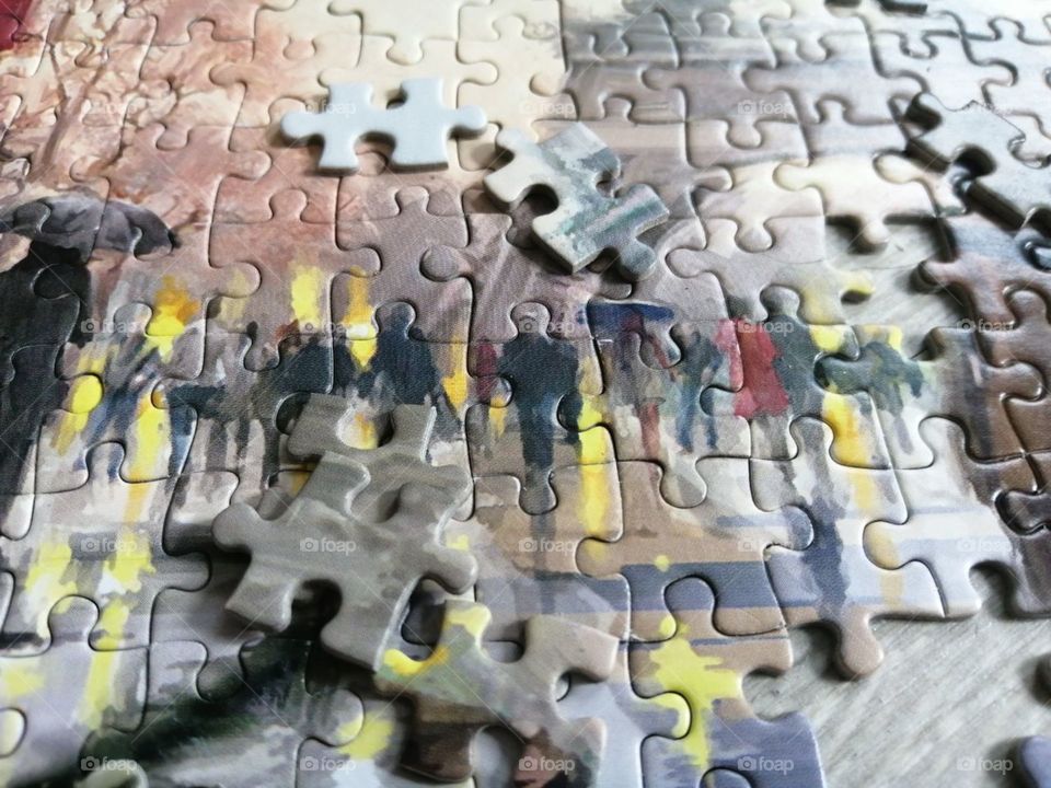 Partially assembled picture of puzzles on grey floor close-up