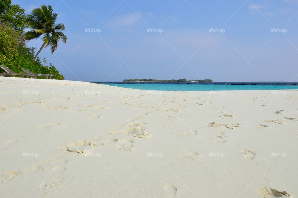 Sunny tropical beach with atoll on the horizon