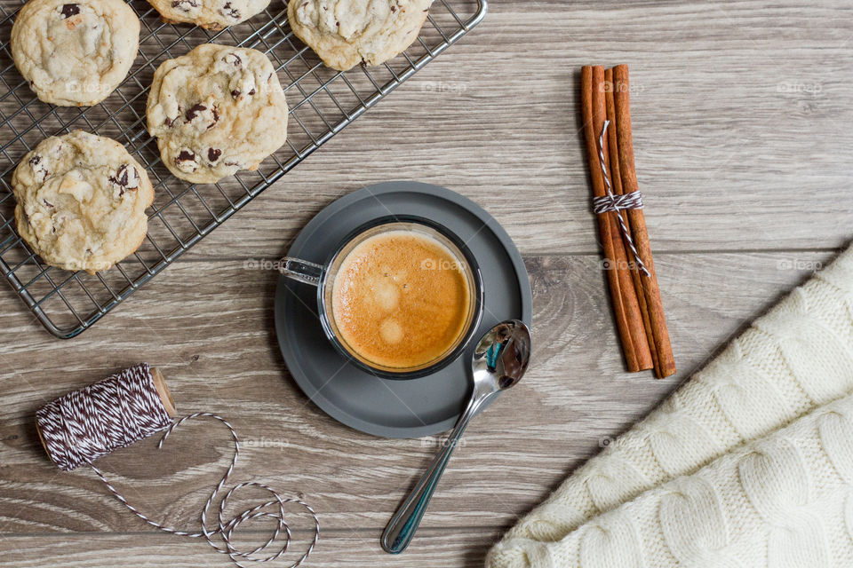 A cup of fresh espresso styled with cookies and a warm blanket