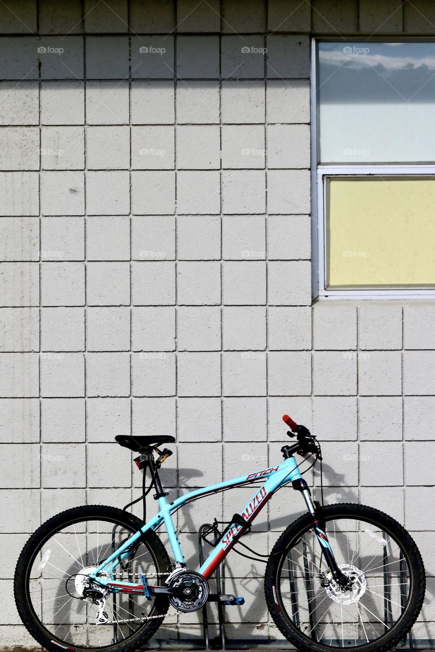 Turquoise blue riderless bike bicycle leaning isolated against outdoor white tiled wall, room for text 