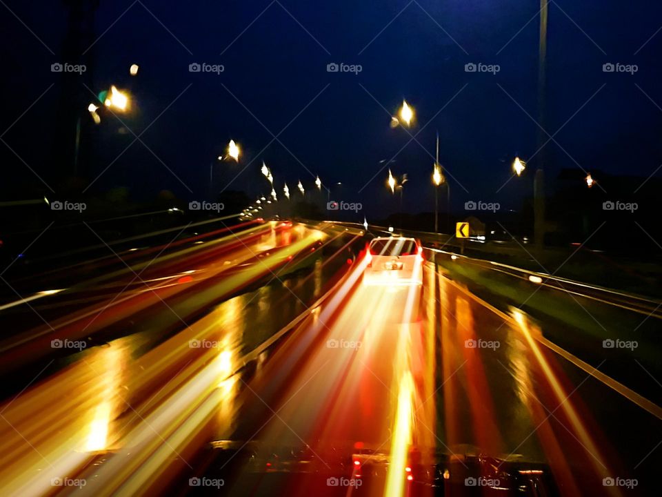 View of highway driving in heavy rain, rain at night, slippery road, few vehicle, light traffic, car heahlights sparkling, light reflecting off the road surface, beautiful outdoor scenery