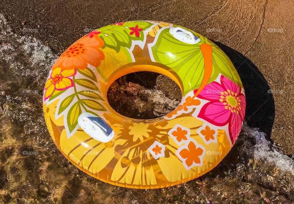 Bright floatie floating on water by the shore