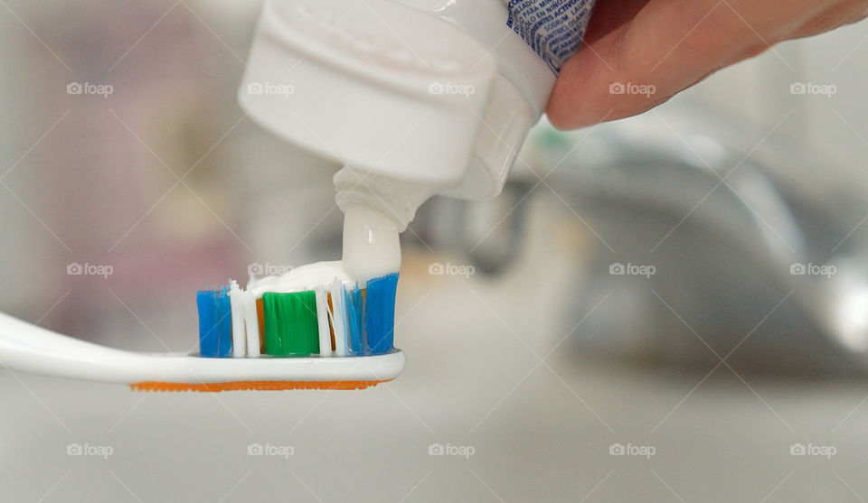 Person squeezing toothpaste on toothbrush