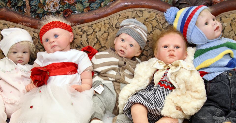 Couch full of realistic looking baby dolls. 