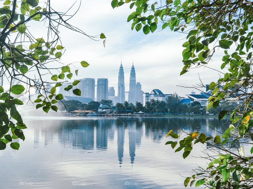 View of Kuala Lumpur skyline across the lake framed through the leaves