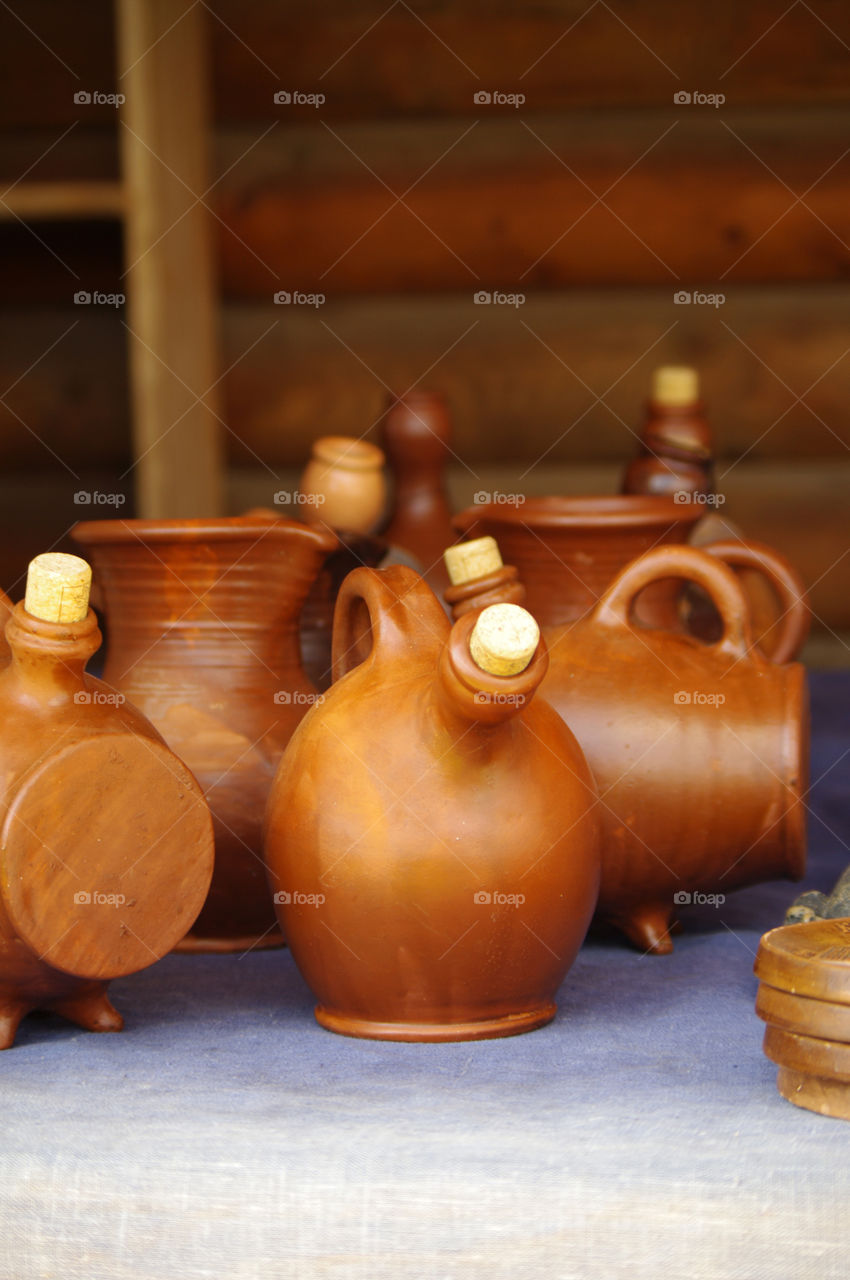 clay pots and vessels stand on a shelf in a rustic kitchen