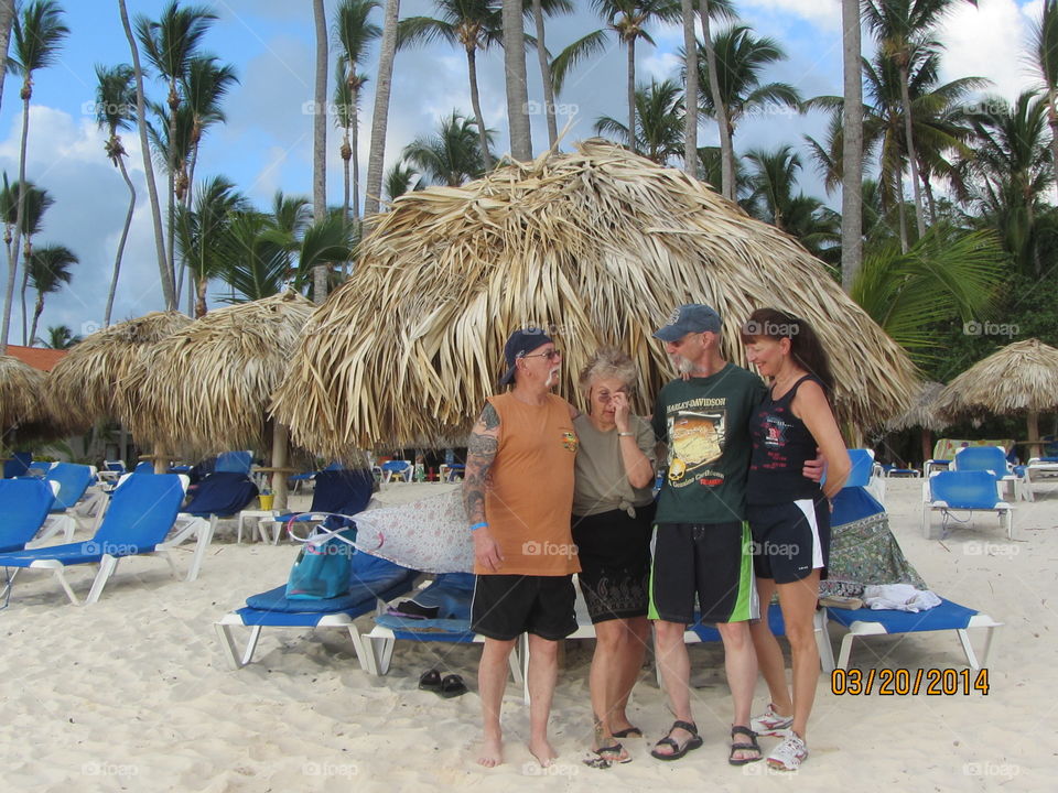 Summer activities in the USA. Friends taking a vacation to a beach resort. Beach umbrellas are made from palm branches.